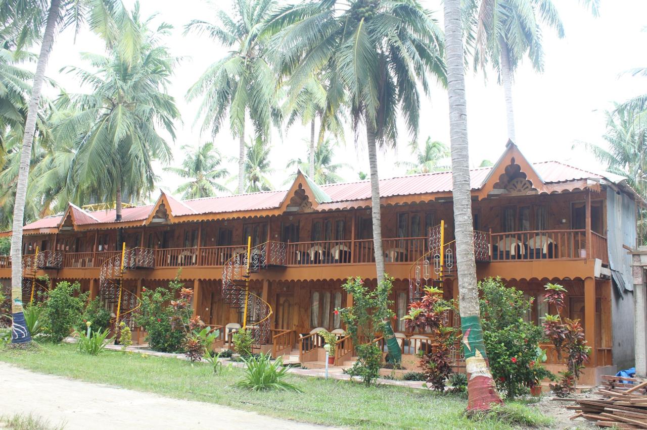 Two-storey resort building among tall coconut palms